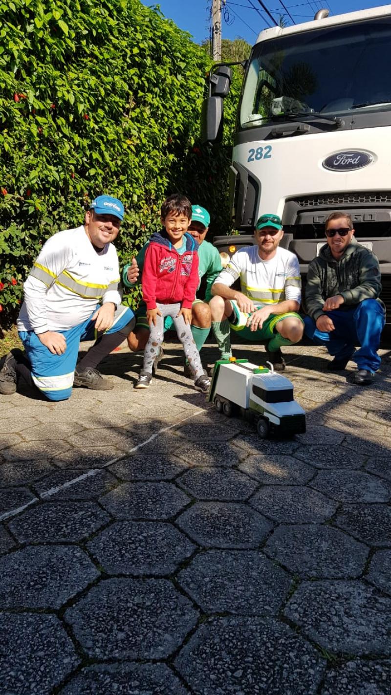 Equipe da coleta presenteia garotinho com réplica do caminhão