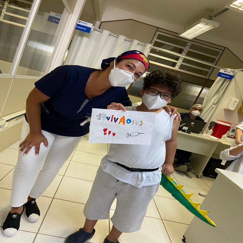 Criança faz desenho para vacinadoras ao se imunizar contra Covid-19